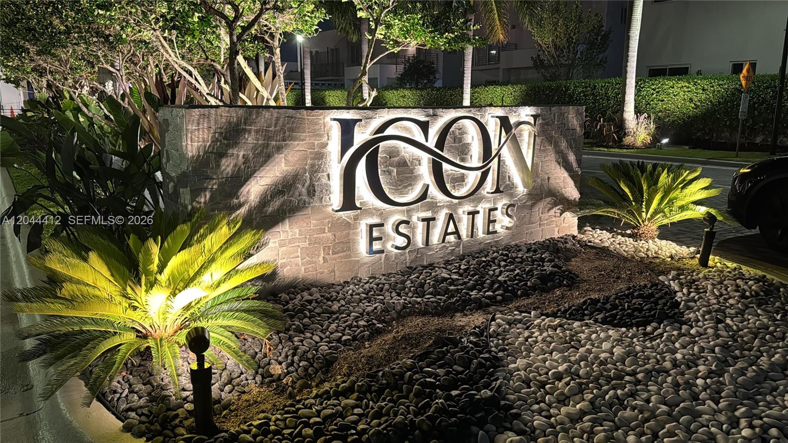 An illuminated stone monument sign for Icon Estates stands in a landscaped garden at night — 10381 NW 67th Ter, Doral FL 33178, DORAL, FL