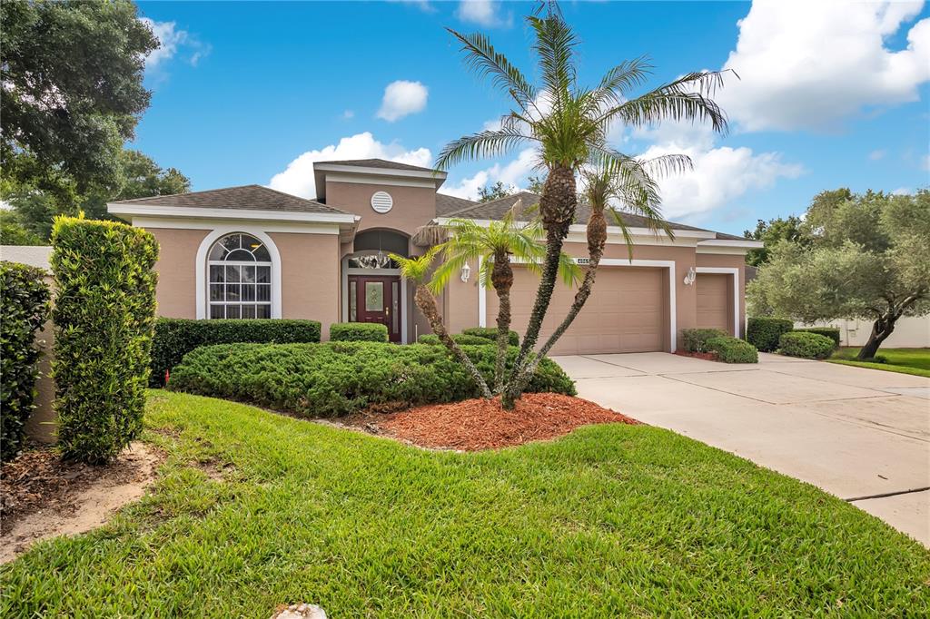 A single-story house with a tan exterior, a two-car garage, and a palm tree — 4065 KINGSLEY STREET, CLERMONT, FL
