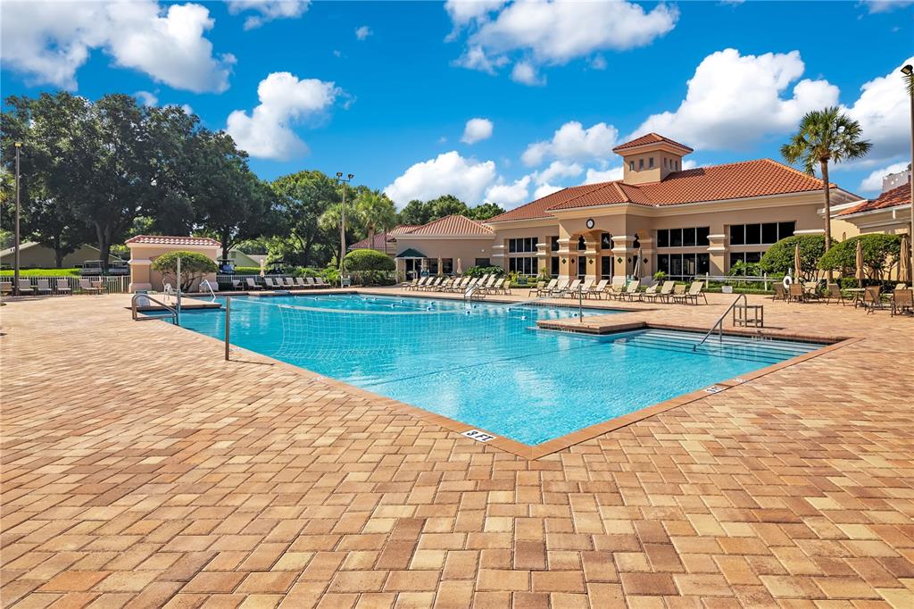 A swimming pool with a volleyball net sits on a brick patio near a building — 4065 KINGSLEY STREET, CLERMONT, FL