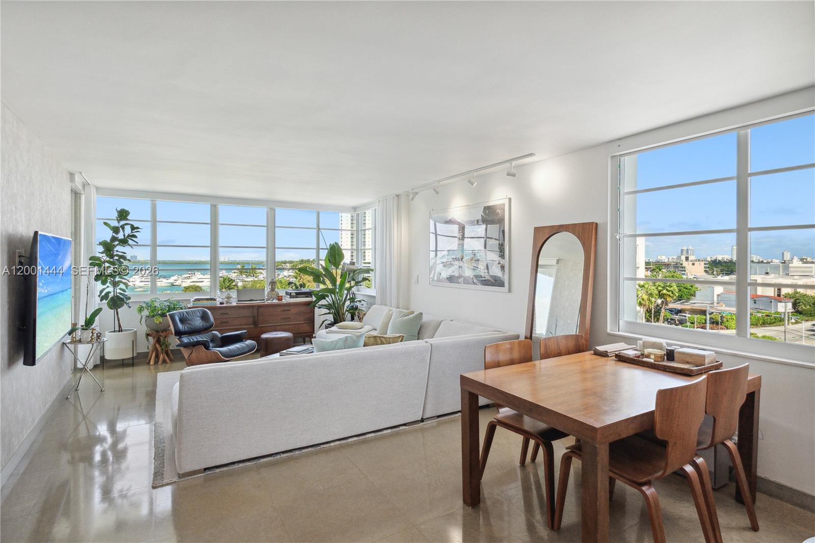 A bright living and dining area features large windows, light tile floors, and modern furniture — 1670 lincoln Ct, Miami Beach FL 33139, MIAMI BEACH, FL