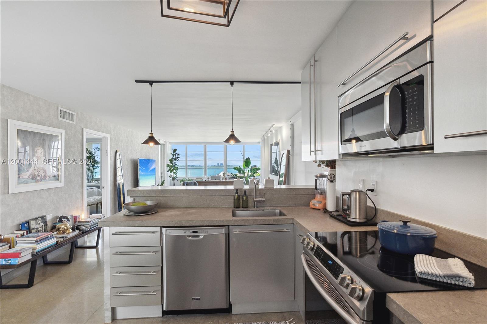 A modern kitchen features stainless steel appliances, concrete countertops, and a view of the ocean — 1670 lincoln Ct, Miami Beach FL 33139, MIAMI BEACH, FL