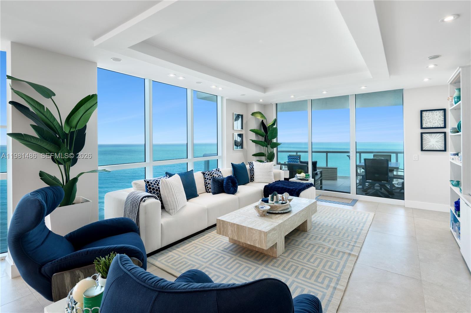 A bright living room features a white sectional, blue accents, and floor-to-ceiling ocean views — 3801 Collins Ave # 1906, Miami Beach FL 33140, MIAMI BEACH, FL