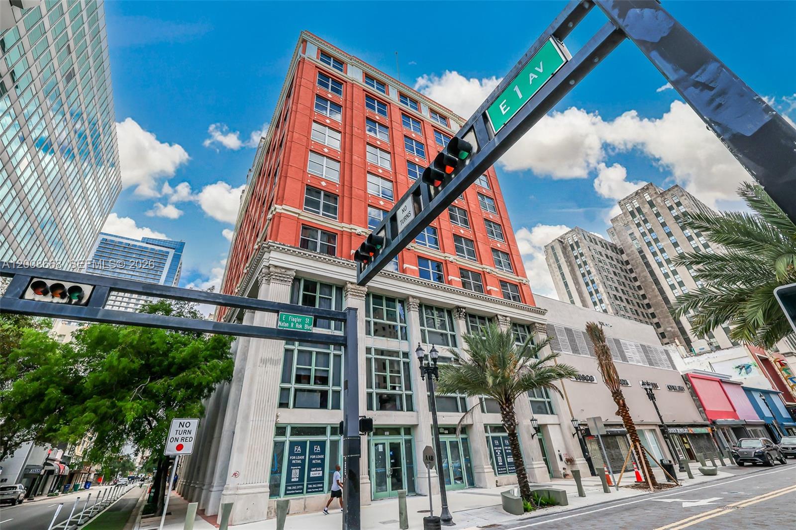 A low-angle exterior view of a red brick historic building at a city intersection — 111 E Flagler St # 708, Miami FL 33131, MIAMI, FL