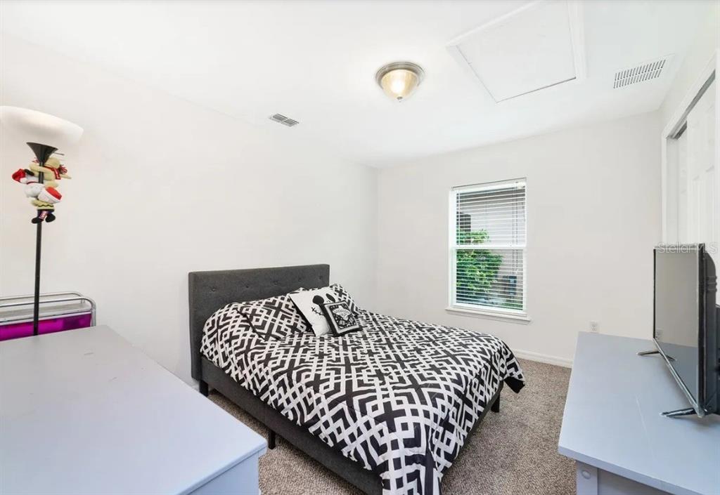 A bedroom features a bed with a black and white patterned comforter and gray furniture — 15649 CARINA DRIVE, ORLANDO, FL