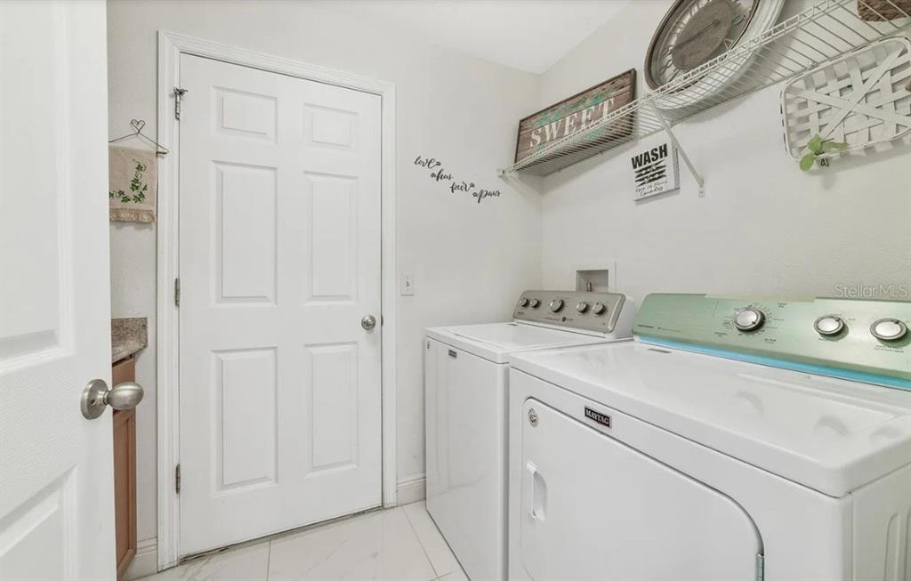 A laundry room features white appliances, a wire shelf, and a white door — 15649 CARINA DRIVE, ORLANDO, FL