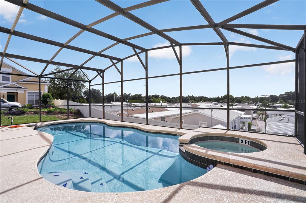 A screened-in pool area features a swimming pool, a raised spa, and a concrete deck — 722 CADIZ LOOP, DAVENPORT, FL