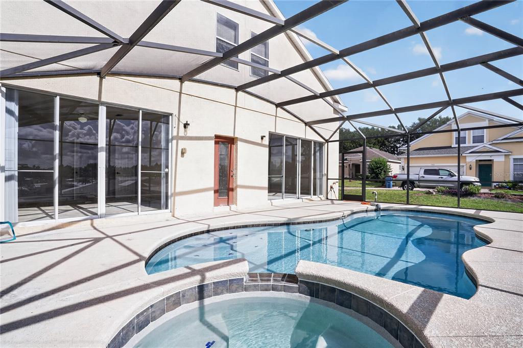 A screened-in patio features a swimming pool and an attached hot tub — 722 CADIZ LOOP, DAVENPORT, FL