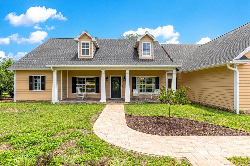 A tan-sided house with a front porch, dormer windows, and a paver walkway — 9041 SW 14TH AVENUE, OCALA, FL
