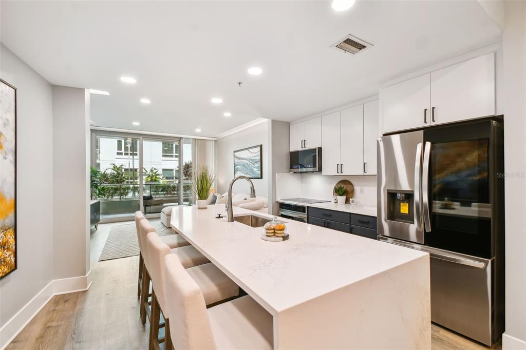 A modern kitchen features a large white quartz island, stainless steel appliances, and light cabinetry — 912 CHANNELSIDE DRIVE UNIT 2316, TAMPA, FL