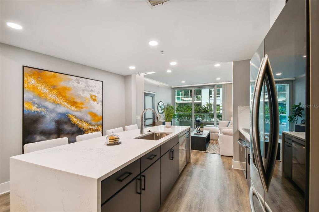 A modern kitchen with a white quartz island, dark cabinets, and an open living area — 912 CHANNELSIDE DRIVE UNIT 2316, TAMPA, FL