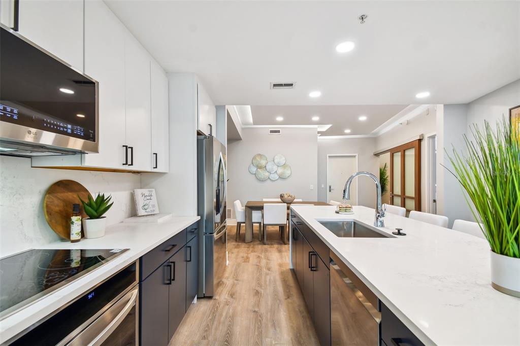 A modern kitchen features dark lower cabinets, white upper cabinets, and a large quartz island — 912 CHANNELSIDE DRIVE UNIT 2316, TAMPA, FL
