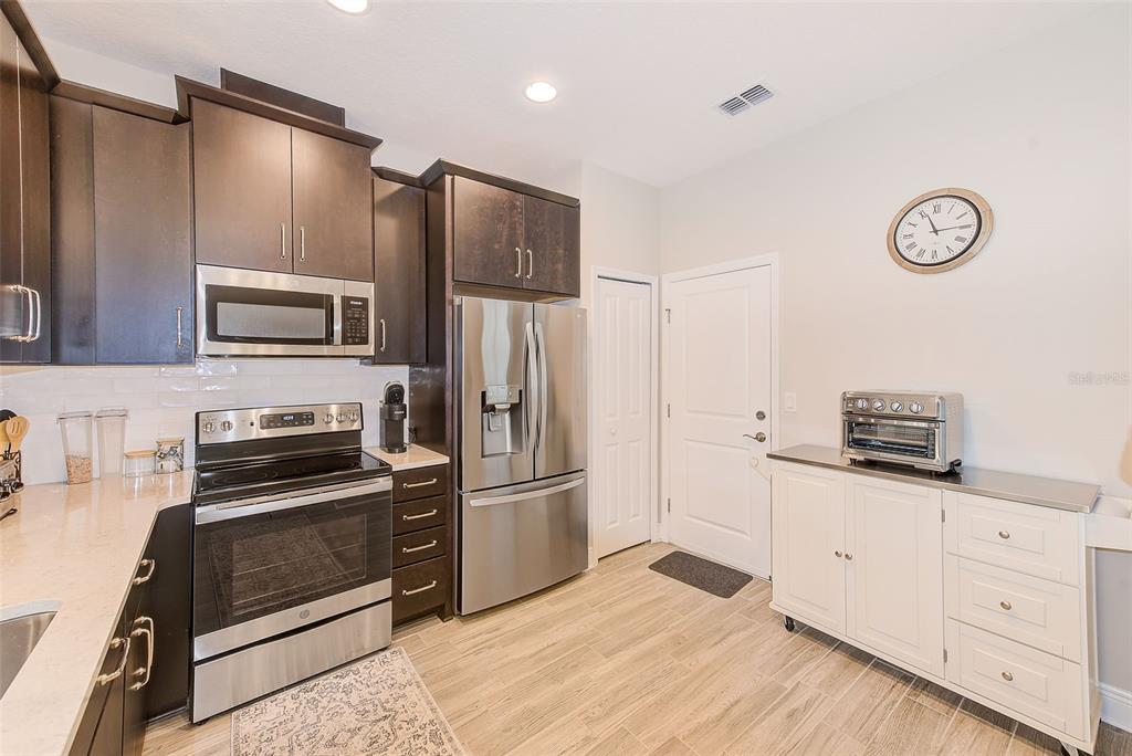 A kitchen features dark wood cabinets, stainless steel appliances, and a white freestanding storage unit — 2441 FOGGY CREEK CIRCLE, CLEARWATER, FL