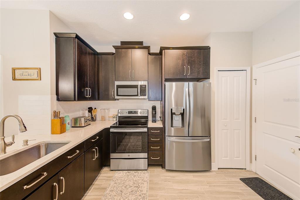 A kitchen features dark wood cabinets, stainless steel appliances, and light countertops — 2441 FOGGY CREEK CIRCLE, CLEARWATER, FL