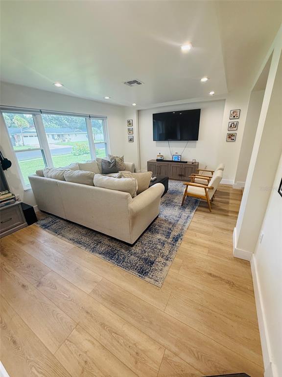 A living room features light wood flooring, a large sectional sofa, and a wall-mounted television — 1956 JAPONICA ROAD, WINTER PARK, FL