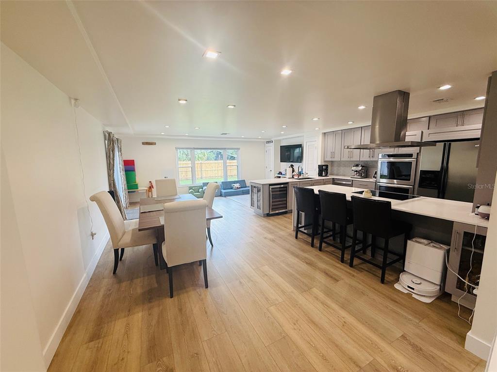 An open-concept kitchen and dining area features light wood flooring, gray cabinetry, and stainless appliances — 1956 JAPONICA ROAD, WINTER PARK, FL