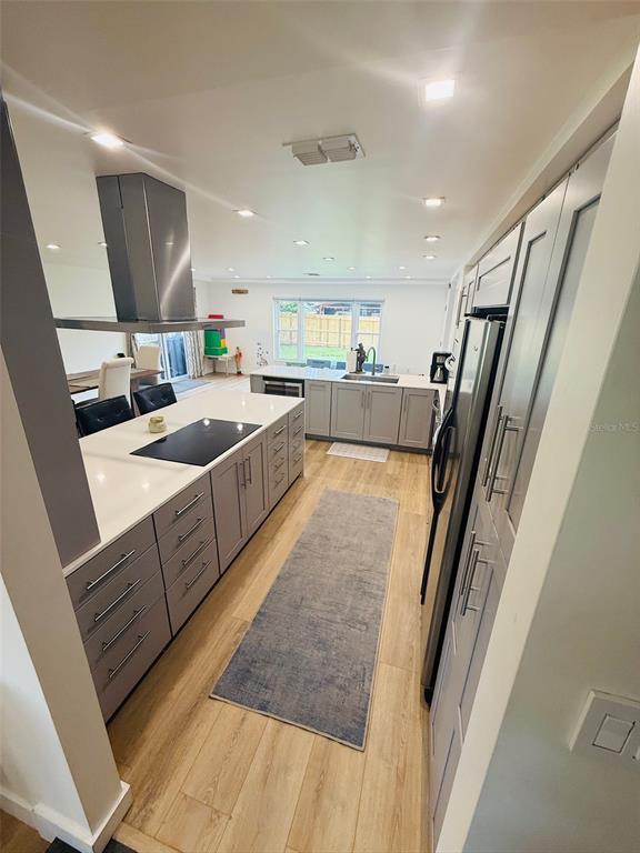 A modern kitchen features light gray cabinets, white countertops, stainless steel appliances, and wood flooring — 1956 JAPONICA ROAD, WINTER PARK, FL