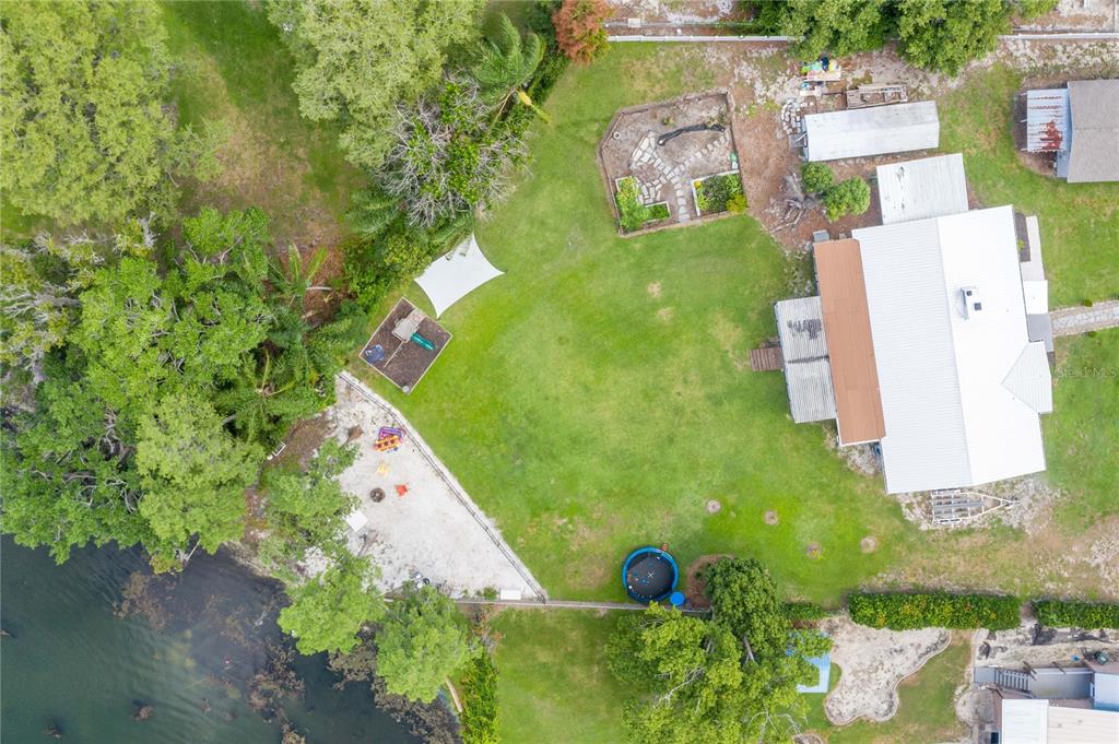 An aerial view shows a house with a large backyard, playground, and waterfront access — 775 S BUENA VISTA DRIVE, LAKE ALFRED, FL
