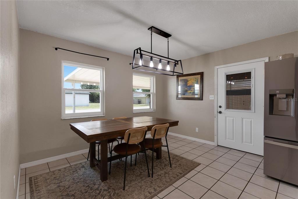 A dining room features a wooden table, four chairs, a rectangular chandelier, and tile flooring — 217 ROSE STREET, AUBURNDALE, FL