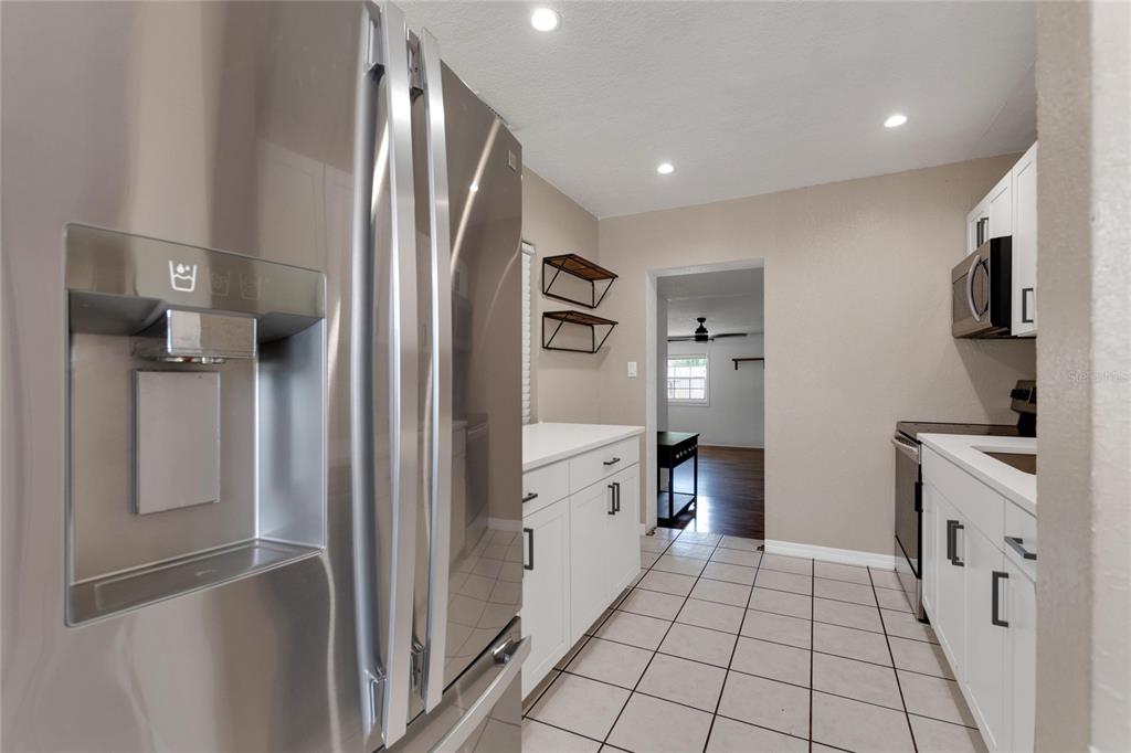 A kitchen with white cabinets, stainless steel appliances, and tiled flooring — 217 ROSE STREET, AUBURNDALE, FL
