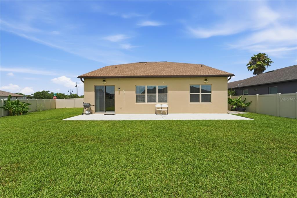 A covered entryway features a front door, potted plants, and a decorative metal trellis — 3699 MOCA DRIVE, ST CLOUD, FL