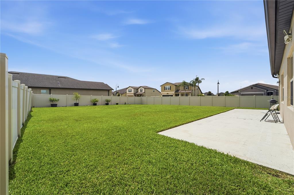 The exterior rear view of a house features a concrete patio and a fenced yard — 3699 MOCA DRIVE, ST CLOUD, FL