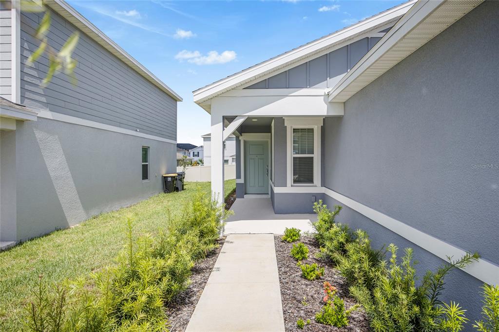 A concrete walkway leads to the light blue front door of a gray house — 2235 LOVELY LANE, DAVENPORT, FL