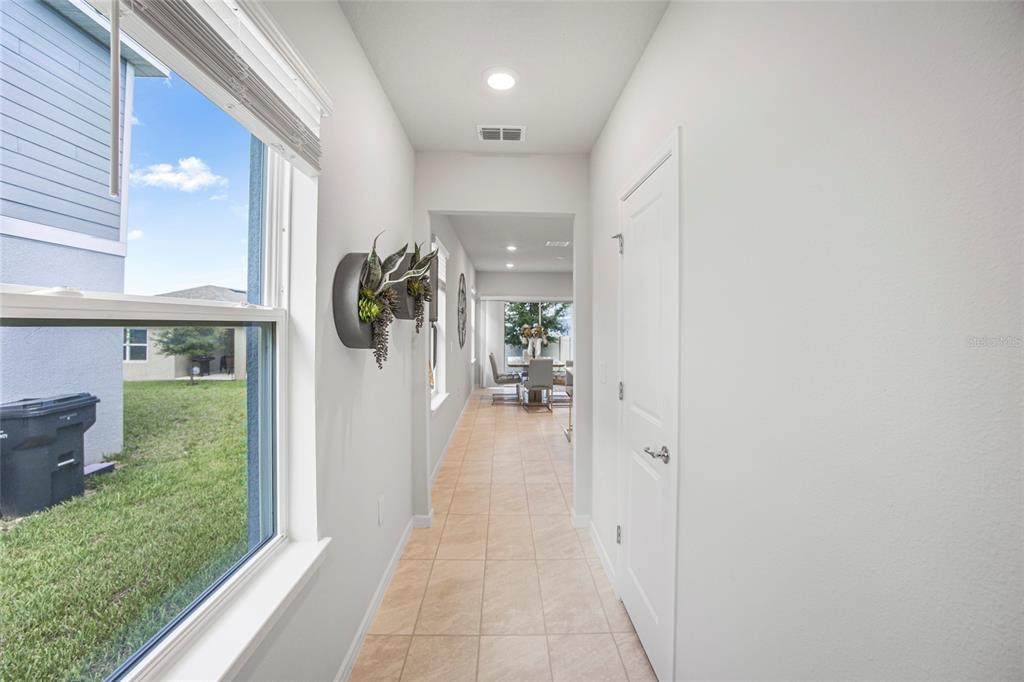 A hallway with tile flooring leads toward a dining area, featuring a window and door — 2235 LOVELY LANE, DAVENPORT, FL