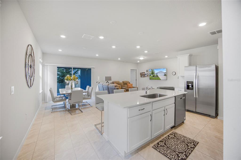 A bright open-concept kitchen with a white island overlooks a dining area and living room — 2235 LOVELY LANE, DAVENPORT, FL