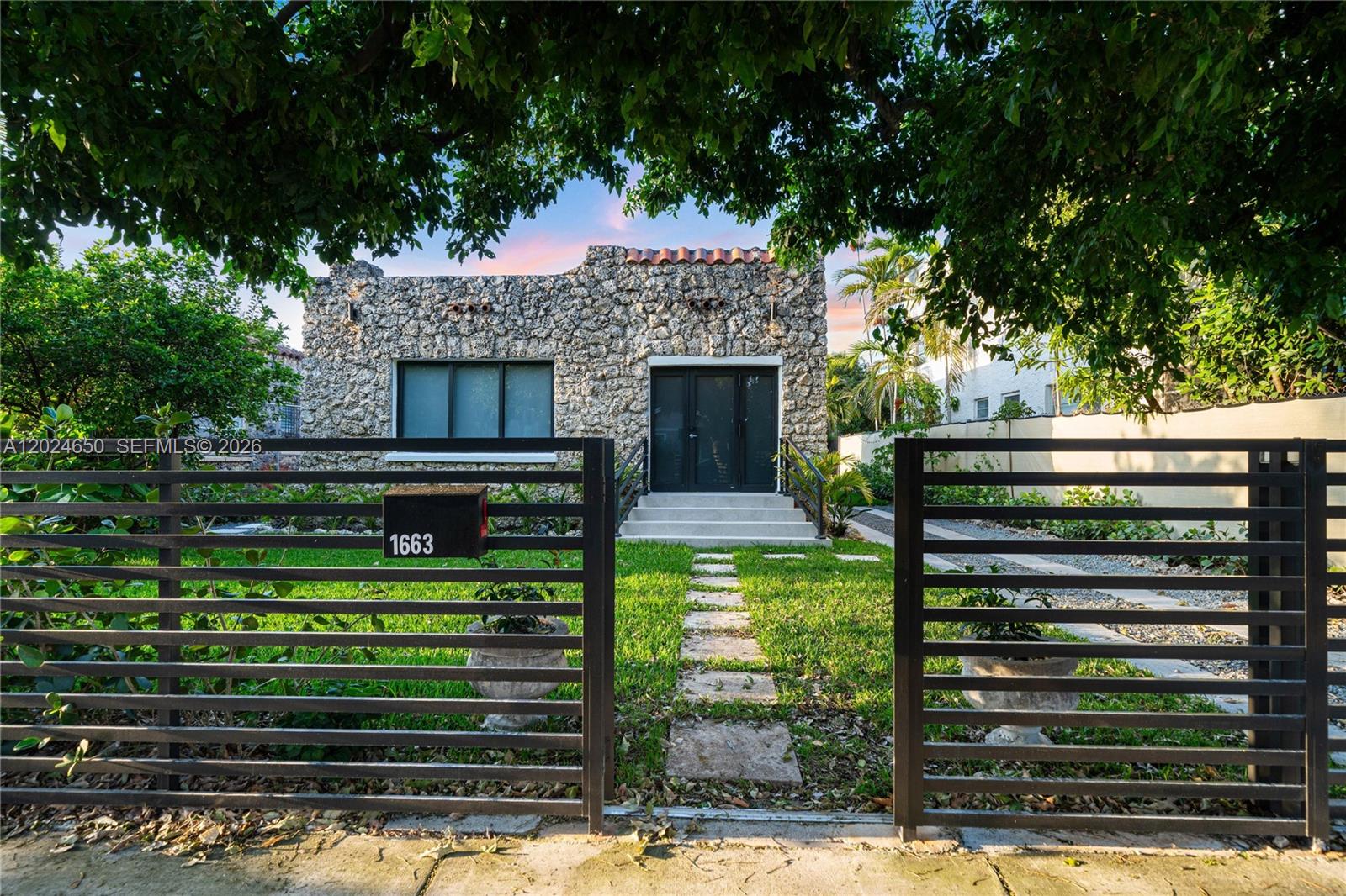A stone-faced house with a black metal fence and a front lawn with stone pavers — 1663 SW 13th St, Miami FL 33145, MIAMI, FL