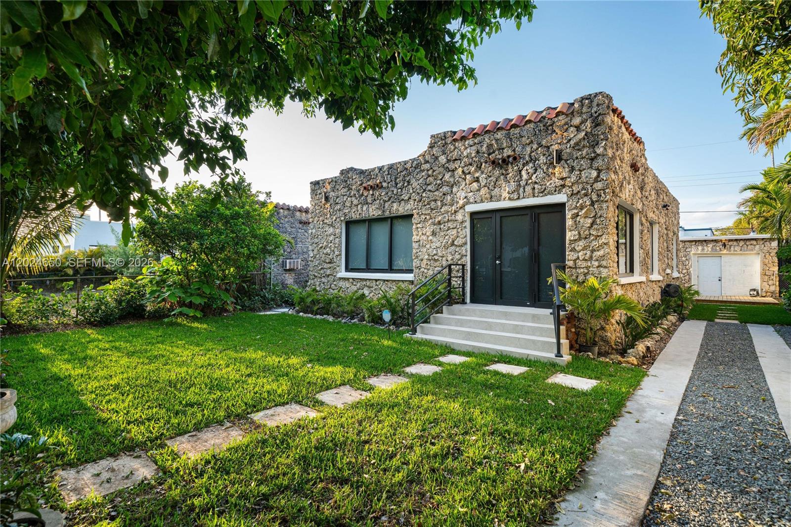 A stone-clad house with a front lawn, gravel driveway, and a set of concrete steps — 1663 SW 13th St, Miami FL 33145, MIAMI, FL