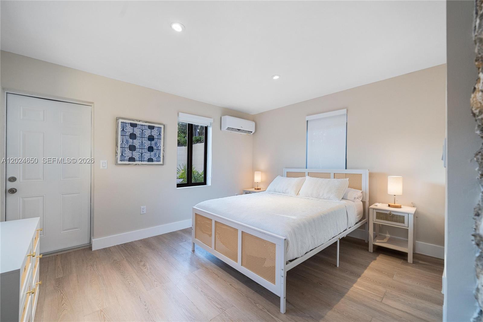 A bedroom features a white bed with cane detailing, light wood flooring, and a mini-split unit — 1663 SW 13th St, Miami FL 33145, MIAMI, FL