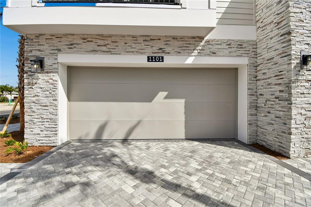 A beige garage door with the number 1101 is set into a stone-clad exterior wall — 3107 TIDEWATCH LOOP, NEW SMYRNA BEACH, FL