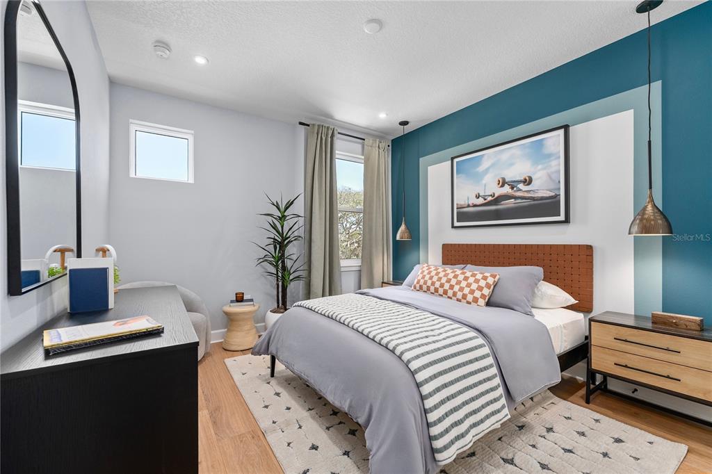 A bedroom features a teal accent wall, a bed with a brown headboard, and wood flooring — 3107 TIDEWATCH LOOP, NEW SMYRNA BEACH, FL