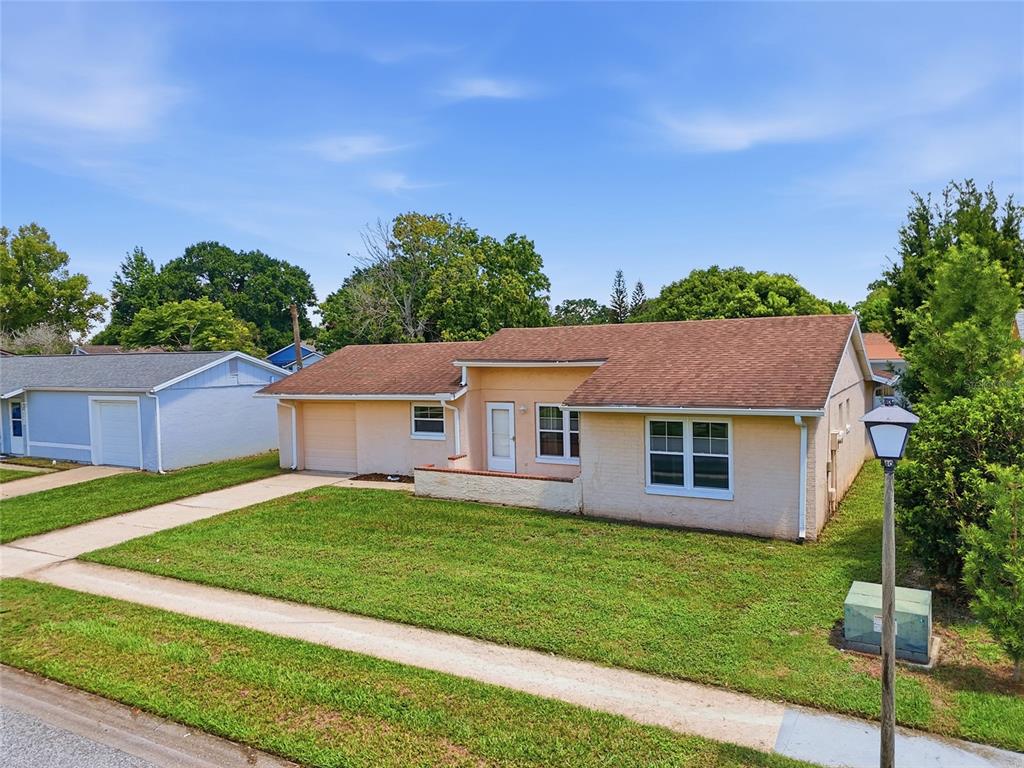 A single-story, light-colored stucco house with a brown shingled roof and a front lawn — 4917 GOUCHER LANE, ORLANDO, FL