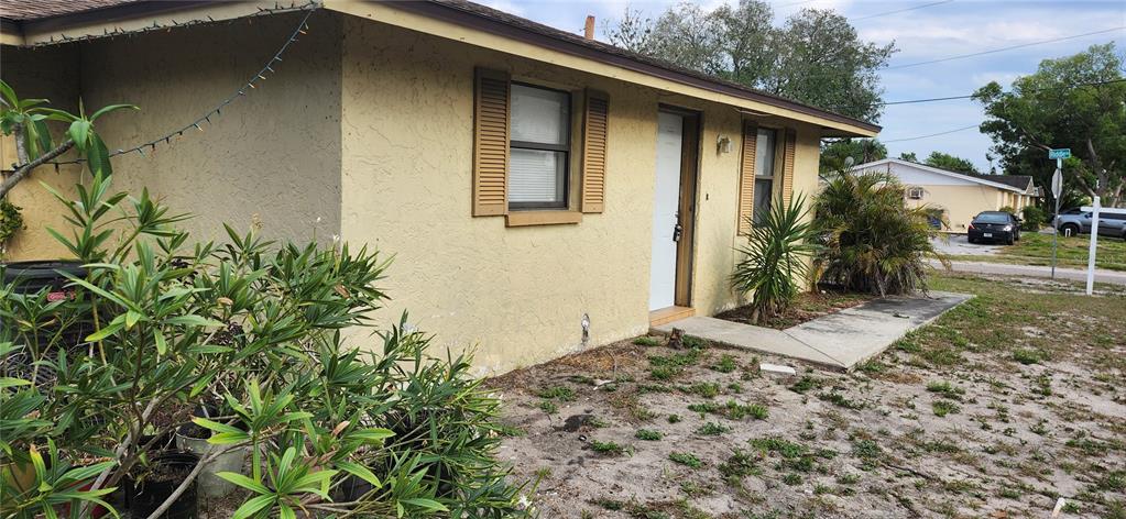 A yellow stucco house exterior with brown shutters, a front door, and a small yard — 5509 RIDDLE ROAD, HOLIDAY, FL