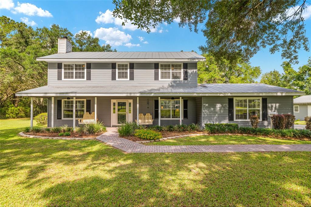 A two-story gray house with a metal roof and a brick walkway in the yard — 12014 NW 136TH STREET, ALACHUA, FL