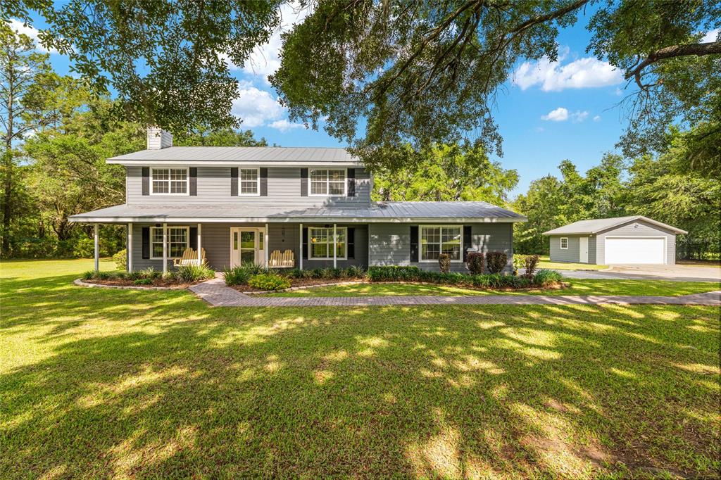 A two-story gray house with a metal roof and a detached garage on a lawn — 12014 NW 136TH STREET, ALACHUA, FL