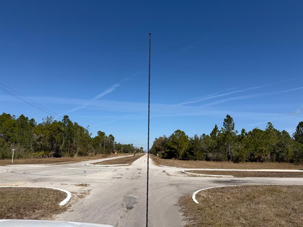 A view of a paved intersection surrounded by trees under a clear blue sky — 923 GAILLARDIA DRIVE, INDIAN LAKE ESTATES, FL