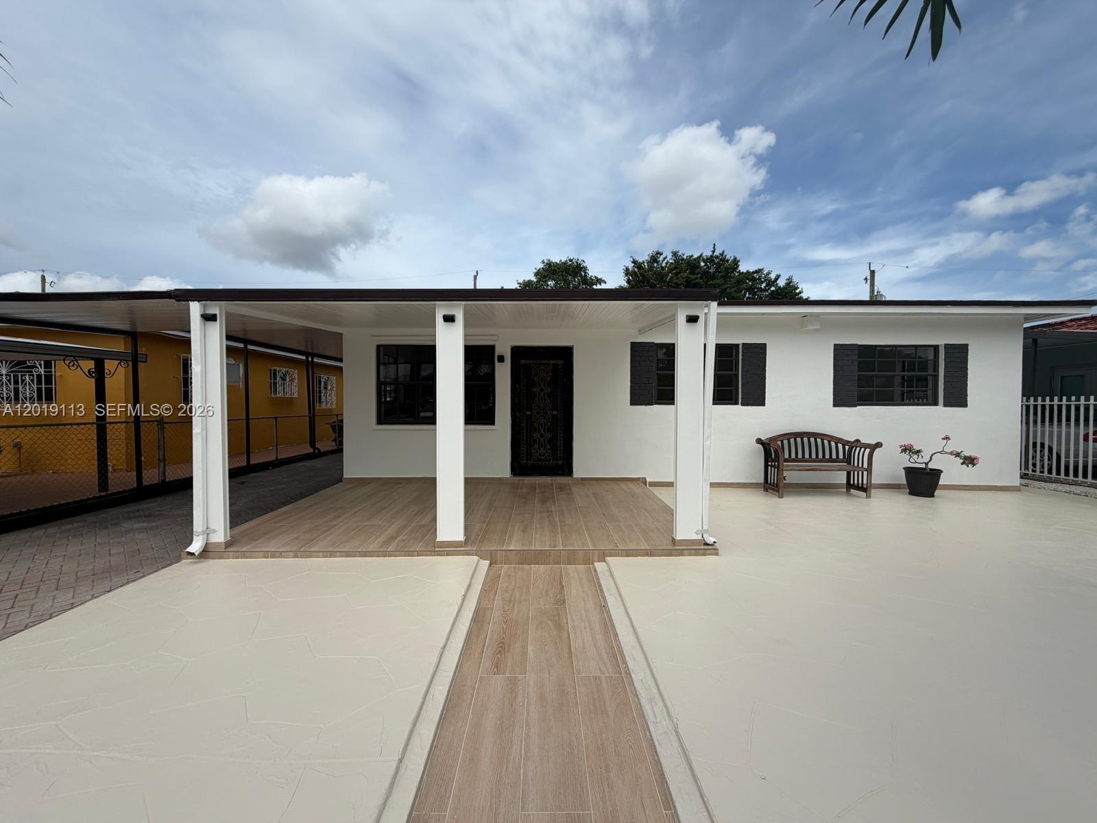 A white house exterior features a covered porch with wood-look tile and a paved driveway — 2541 W 10th Ave, Hialeah FL 33010, HIALEAH, FL