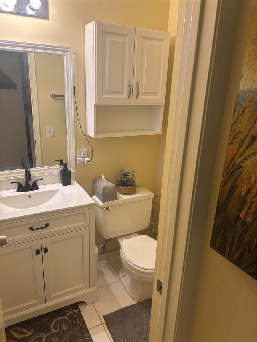 A bathroom features a white vanity, a toilet, and a wall-mounted cabinet against yellow walls — 6670 Royal Palm Boulevard # 308k, Margate FL 33063, MARGATE, FL