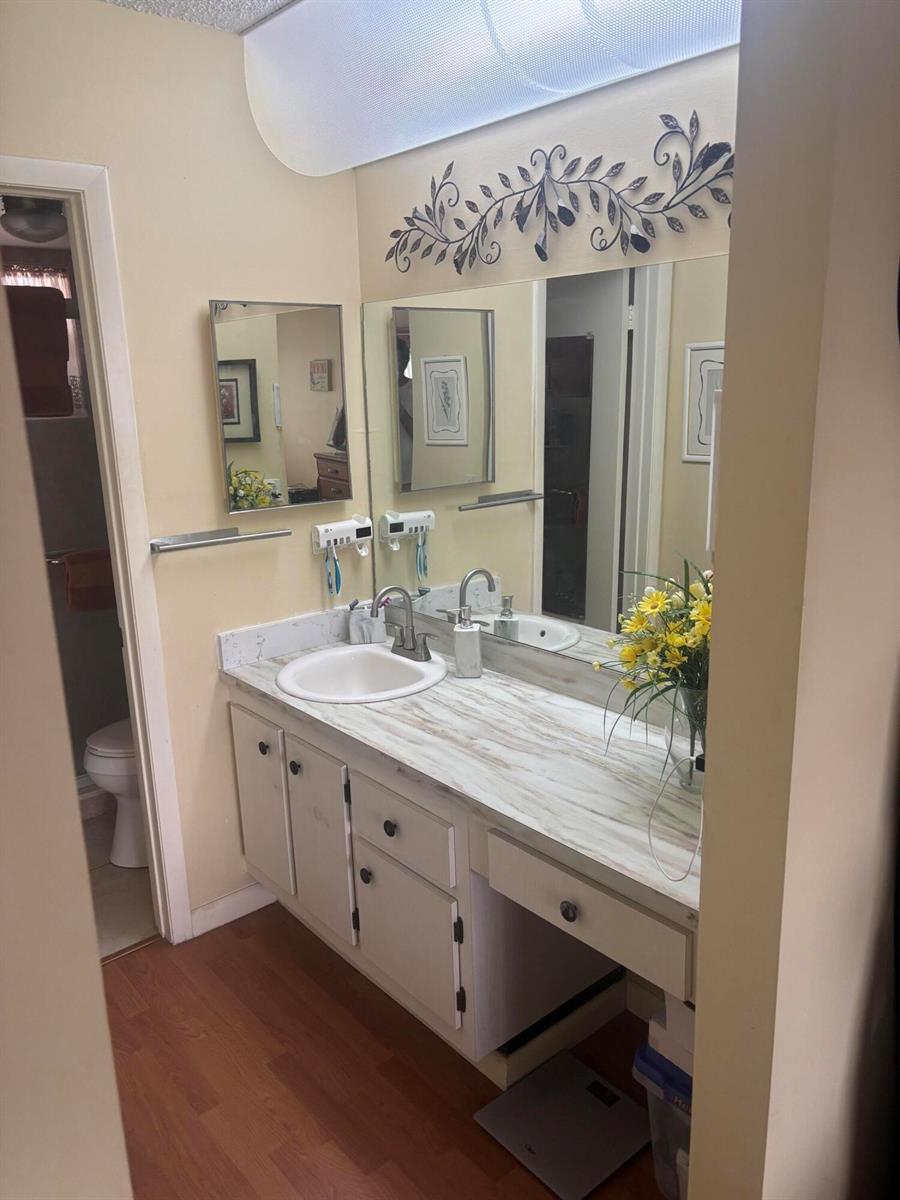 A bathroom features a white vanity with a faux-marble countertop, a large mirror, and lighting — 6670 Royal Palm Boulevard # 308k, Margate FL 33063, MARGATE, FL