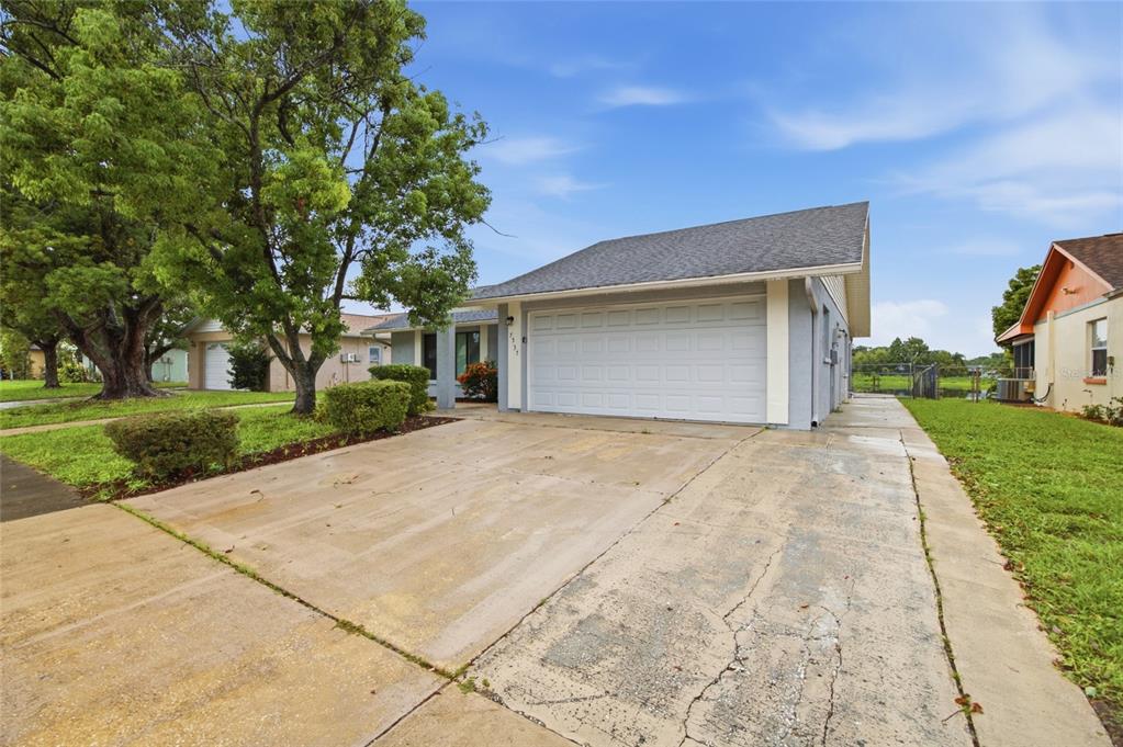 A single-story house with a white garage door and a concrete driveway under a blue sky — 7537 HUMBOLDT AVENUE, NEW PORT RICHEY, FL