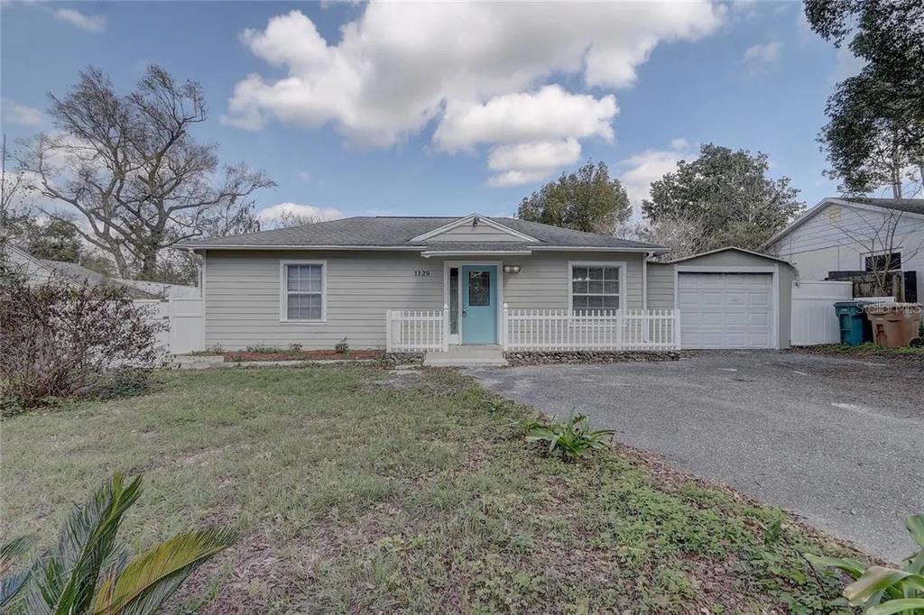 A single-story house with light gray siding, a blue front door, and an attached garage — 1129 NE 12TH STREET, OCALA, FL