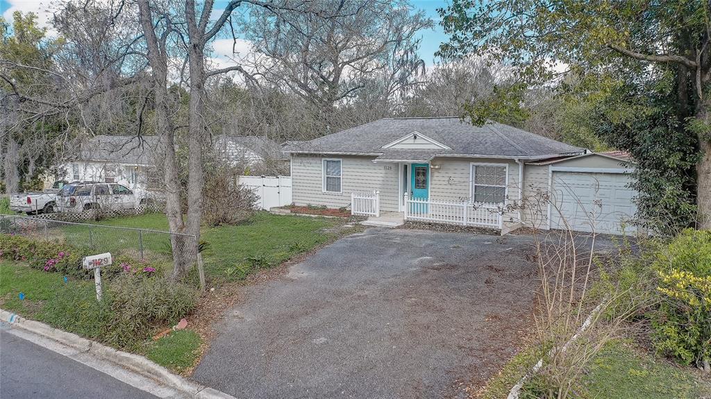 A single-story house with light siding, a blue front door, and an attached garage — 1129 NE 12TH STREET, OCALA, FL