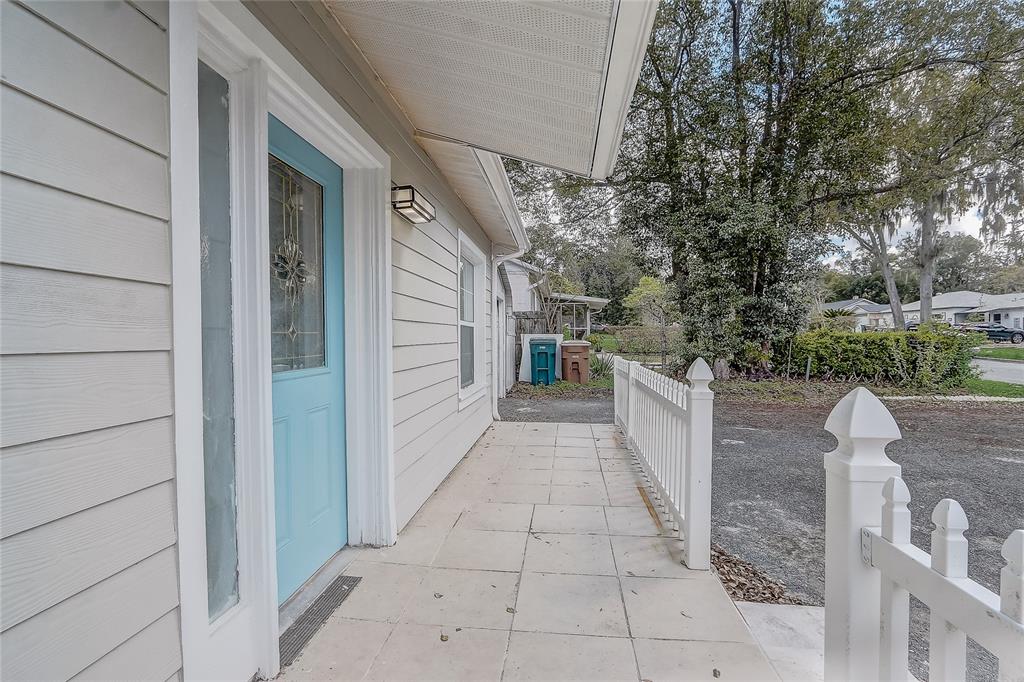 A light blue front door opens onto a tiled porch with a white picket fence — 1129 NE 12TH STREET, OCALA, FL