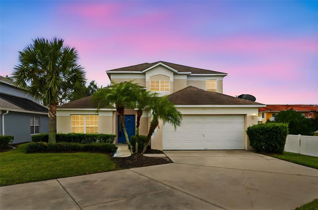 A two-story suburban house with a white garage, palm trees, and a sunset sky — 1145 SEASONS BOULEVARD, KISSIMMEE, FL