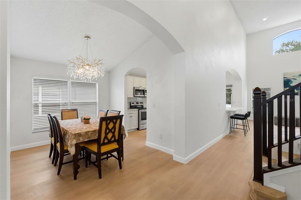 A dining area with a chandelier and a kitchen visible through an arched doorway — 1145 SEASONS BOULEVARD, KISSIMMEE, FL