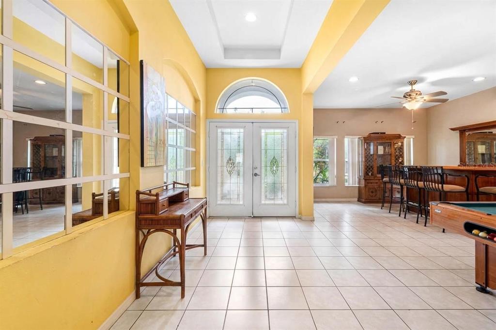 A tiled entryway features a wooden console table, a large wall mirror, and double doors — 444 YORK DALE DRIVE, RUSKIN, FL