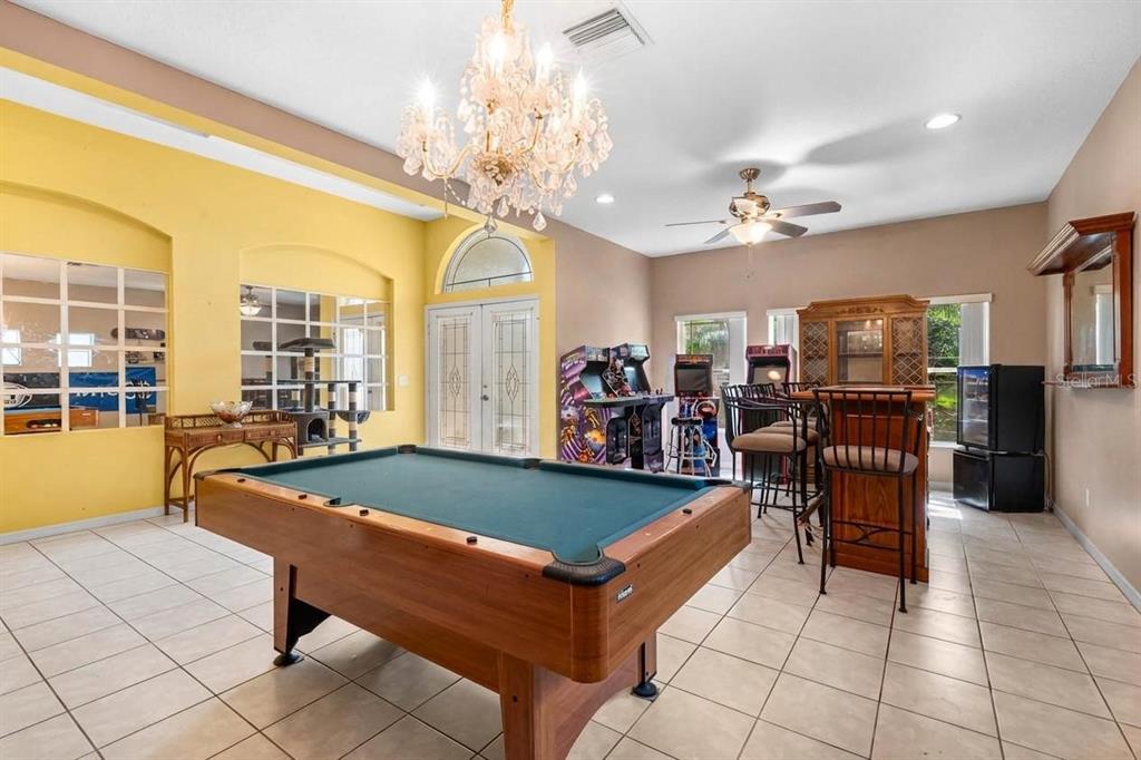 A game room features a pool table, arcade cabinets, a bar, and a crystal chandelier — 444 YORK DALE DRIVE, RUSKIN, FL