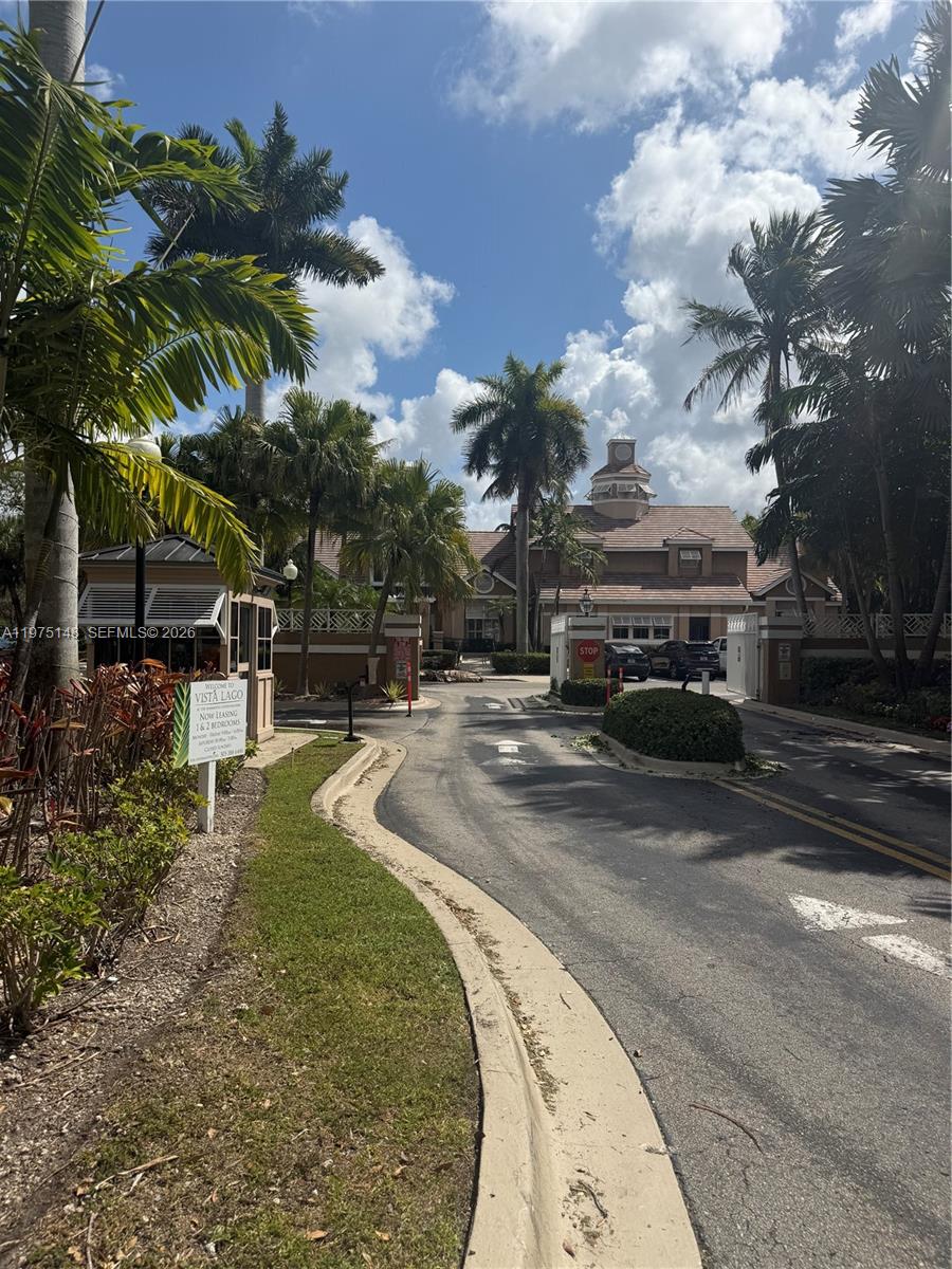 The entrance to the Vista Lago apartment complex features a gated driveway and palm trees — 15680 SW 106th LN # 803, Miami FL 33196, MIAMI, FL